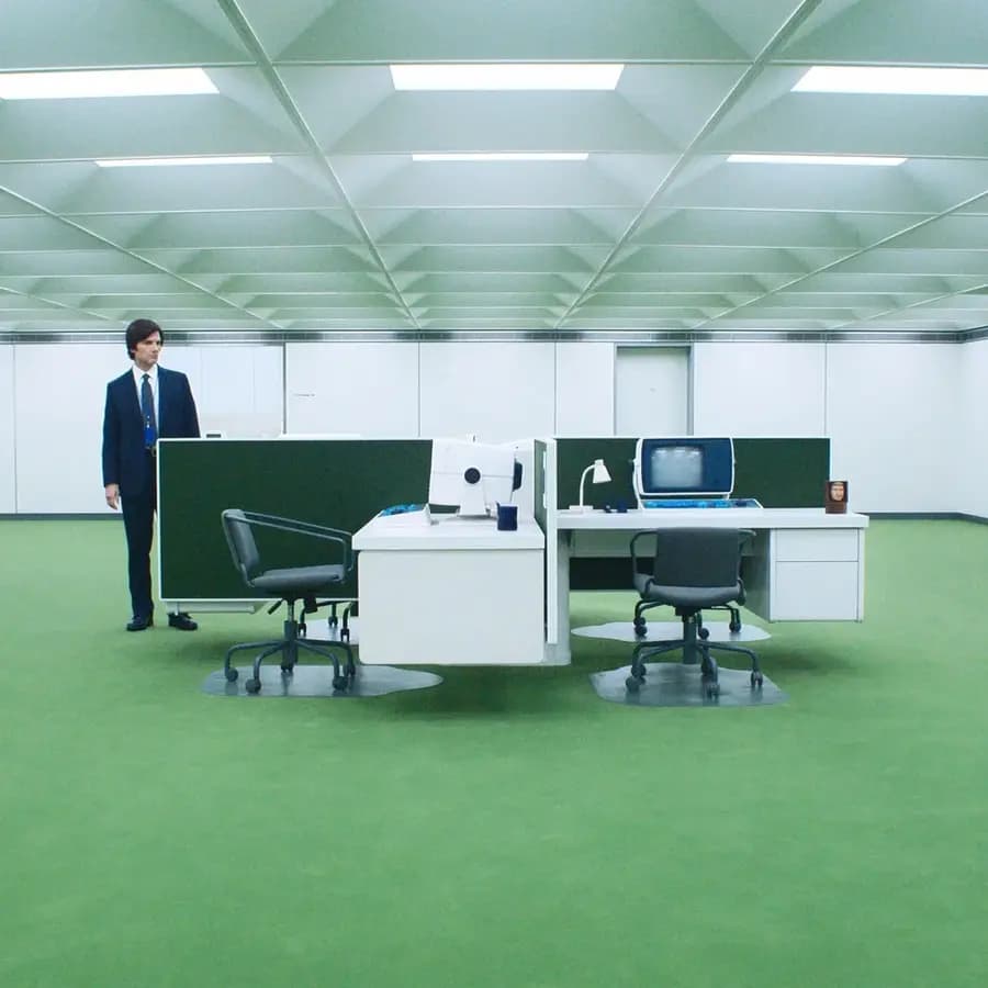 A retro office production set from Severance with green carpet and two desks.